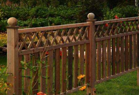 Чтобы оформить привлекательнее сплошной забор из дерева, можно установить небольшую решетку декоративного вида